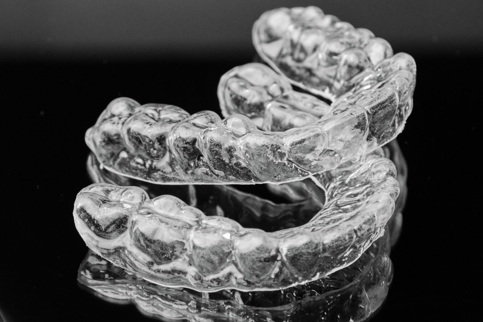 Invisible transparent dental removable braces on the black background. Orthodontic appliance for dental correction. Aligners for teeth straightening